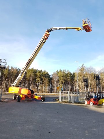 An aerial lift at a construction site near trees.