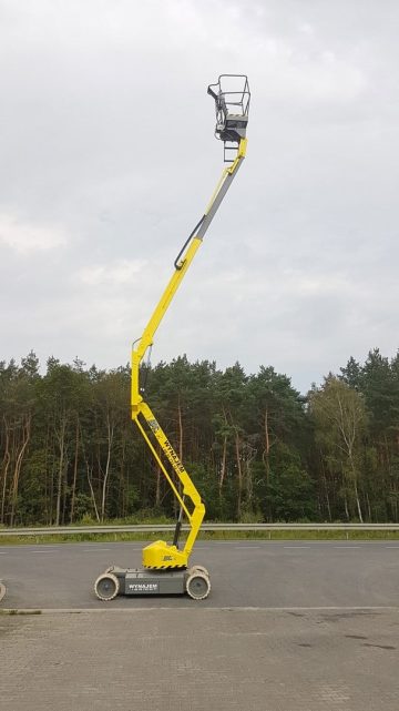 Podnośnik koszowy na parkingu przed lasem.