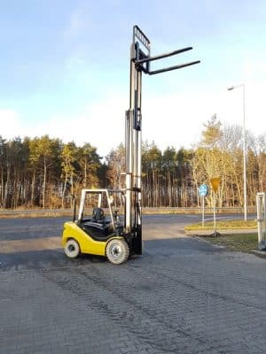 A yellow forklift on an asphalt yard.