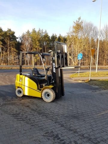 A yellow forklift on an asphalt yard.