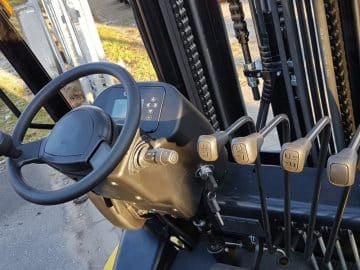 Forklift cab, steering wheel and control levers.