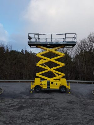 Yellow scissor lift in the parking lot.