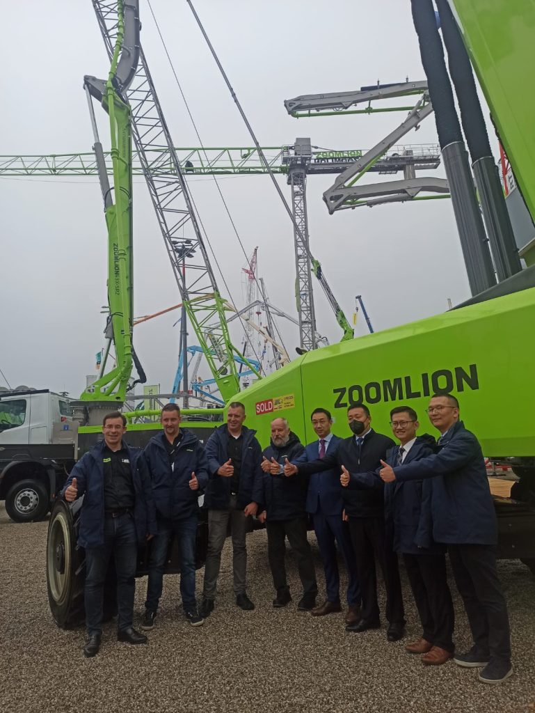 A group of people in front of Zoomlion construction cranes.