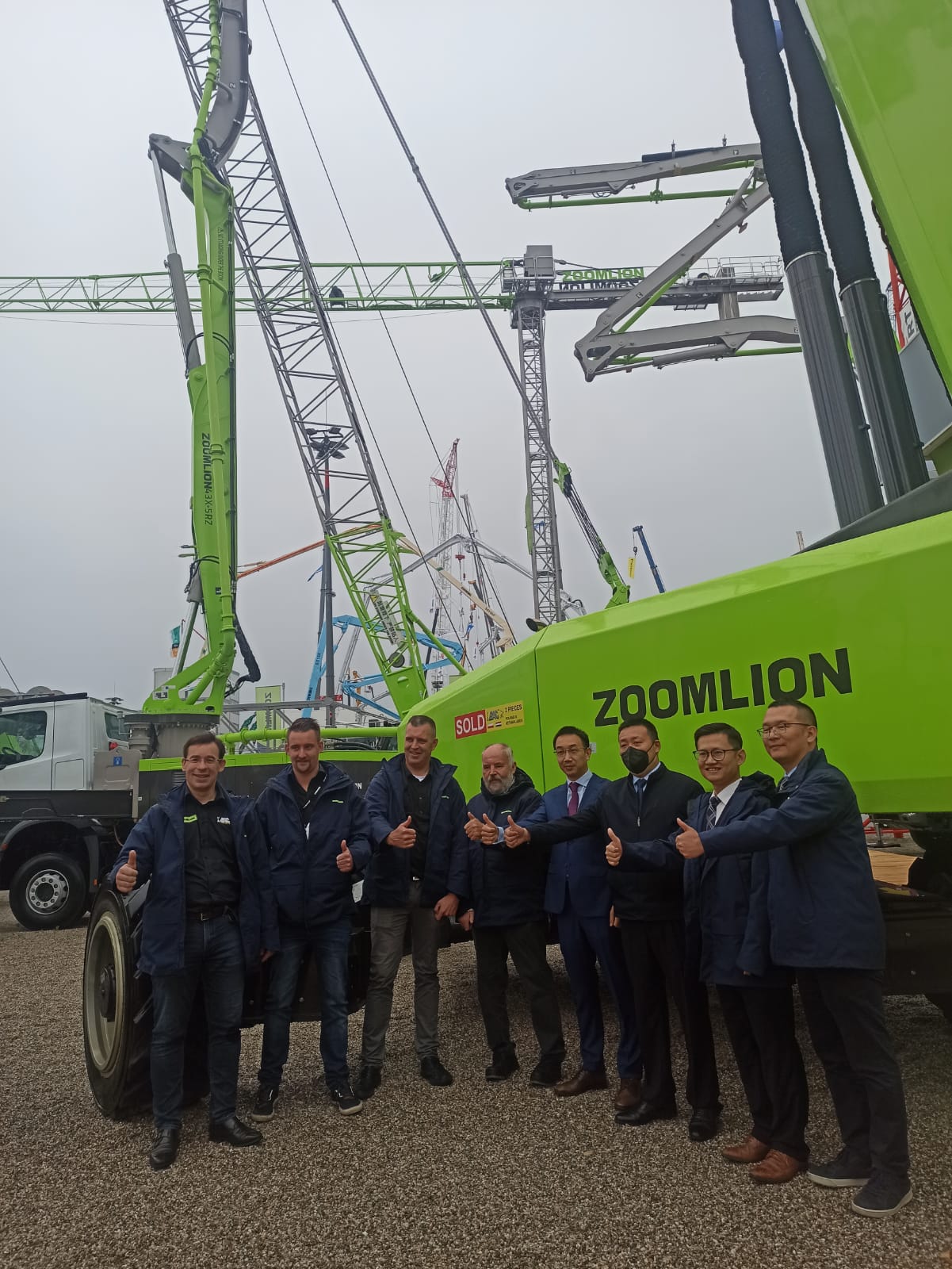 A group of people in front of Zoomlion construction cranes.