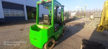 A green forklift in a warehouse yard.