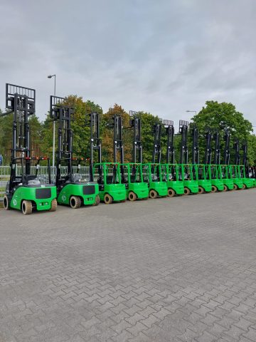 Green forklifts in a row outside.