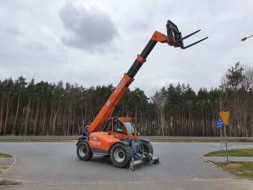 Oranžový teleskopický nakladač pri lesnej ceste