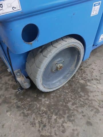 A used tire on the wheels of a blue container.
