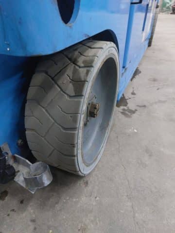 Opotrebovaná pneumatika vysokozdvižného vozíka na betóne.