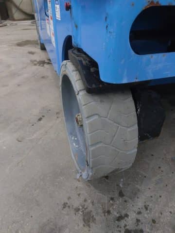 A blue forklift with a damaged tire.