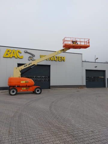 A scissor lift in front of a building with a sign reading "Rental."