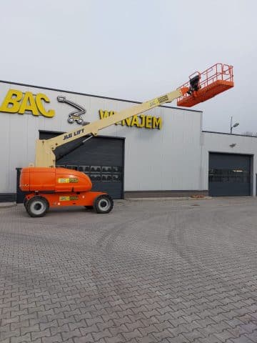 A JLG scissor lift in front of a building with a rental sign.