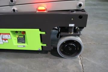 Zelený vysokozdvižný vozík, kolesá v popredí a ovládací panel.