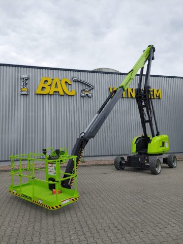 Green scissor lift in front of the warehouse.